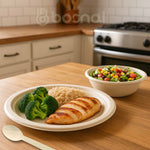 Plated meal with chicken, broccoli, and rice on a wooden table, with a bowl of salad in the background.